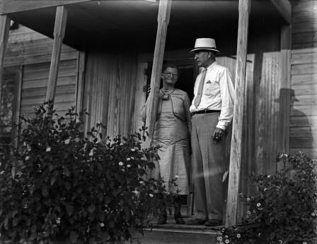 Amon G. Carter and an unidentified woman standing on a front porch