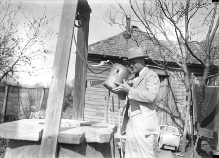 Tex Rickard drinking from the well he dug as a youth outside of Rickard's family home in Henrietta, Texas