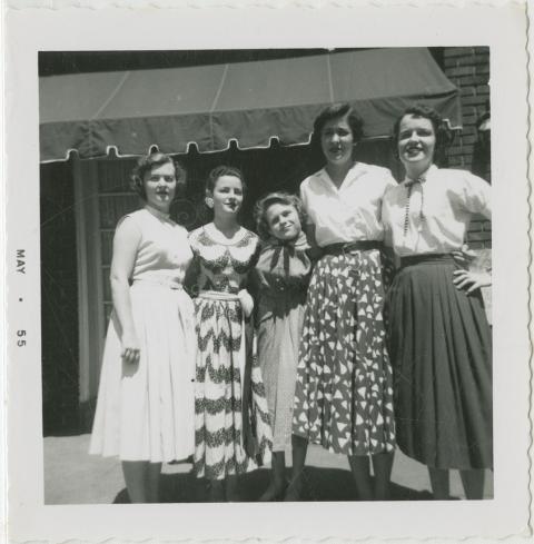 Shirley Sue Smith (center) and four female friends posing in front of a store with an awning, May 1955
