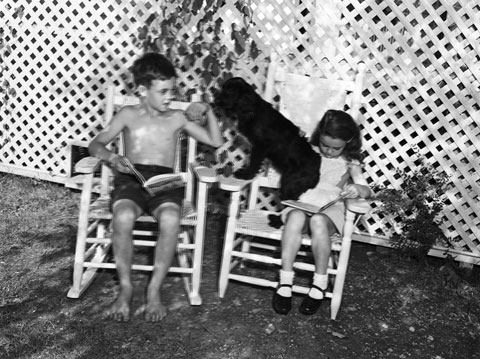children sit in the shade with their pet dog