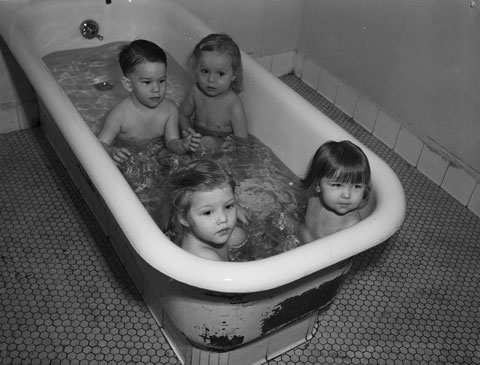 Four young polio patients are sitting in a bathtub