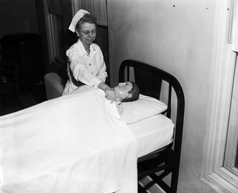 nurse adjusting bedding for the school's dummy used to train nurses