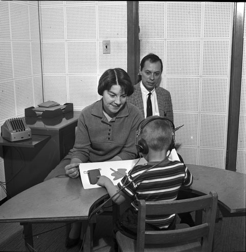 speech therapists work with a male child patient wearing headphones