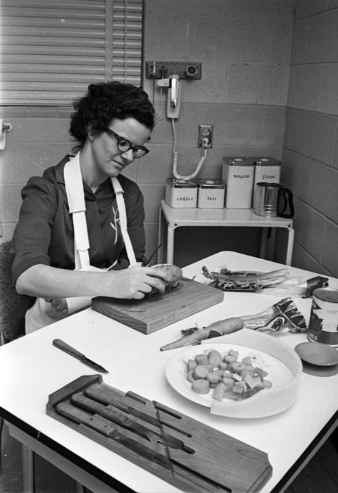 woman learns how to peel a potato in a special-equipment kitchen at rehabilitation center