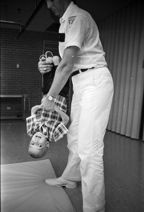 Physical therapist works with boy as they engage in an upside down swinging exercise