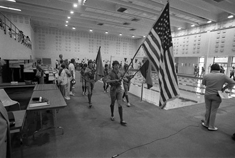 group of 5 young men in Boy Scout uniforms, 3 of which are holding flags