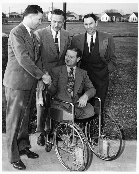 man in wheelchair with three men standing behind him