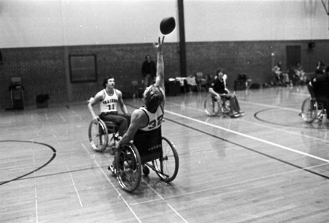 college students play wheelchair football in a high school gymnasium