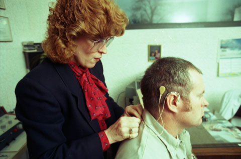 woman hooks up a new hearing device, a cochlear implant