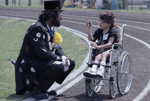 Wheelchair race competitor talks with a clown at the regional Special Olympics games 