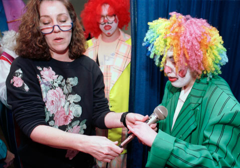  instructor Liz LaRochelle hands microphone to Erin Hendrix dressed as a clown