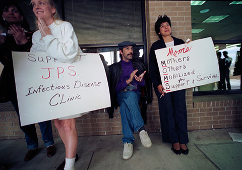 Brad Eddins applauds protesters Kathy Gowan (left) and Terry Carroll who staged a rally at JPS for better AIDS services