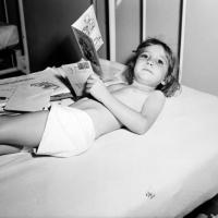 Infantile paralysis convalescent (polio) reads get well cards while laying in bed