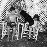 children sit in the shade with their pet dog
