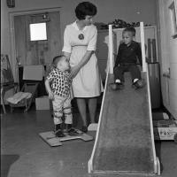 woman assists young patients on a slide
