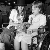 two females sitting in wheelchairs; one has donation can in her lap