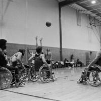 college students play wheelchair basketball in a high school gymnasium