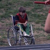 Young boy in wheelchair watches activities along the sidelines at the Special Olympics Games