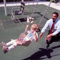 T.Ware, physical therapist, plays with Jeremy Burleson, age 4, on swing set designed for different levels of disability