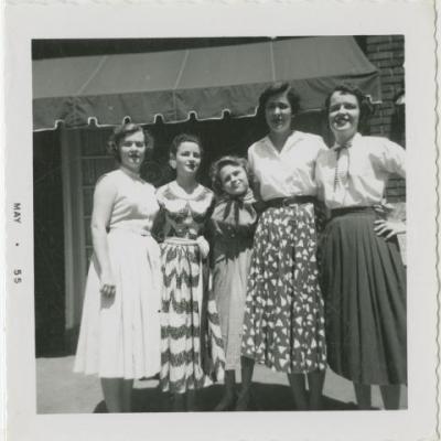 Shirley Sue Smith (center) and four female friends posing in front of a store with an awning, May 1955
