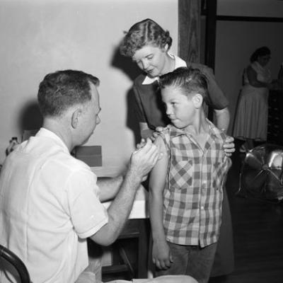 boy receives polio injection at school from physician and school nurse