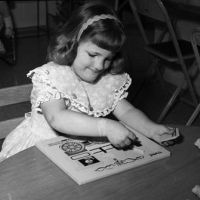 girl works a puzzle in a playroom
