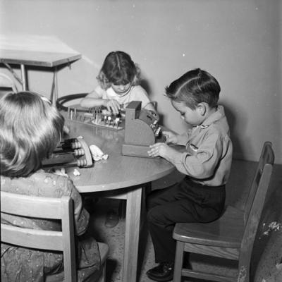 boy plays with a toy cash register while two other children play with other teaching aids