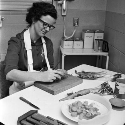woman learns how to peel a potato in a special-equipment kitchen at rehabilitation center