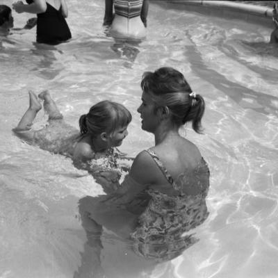 blind child learns to swim with the assistance of an adult aid
