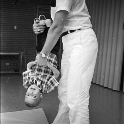 Physical therapist works with boy as they engage in an upside down swinging exercise
