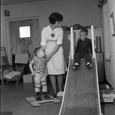 woman assists young patients on a slide