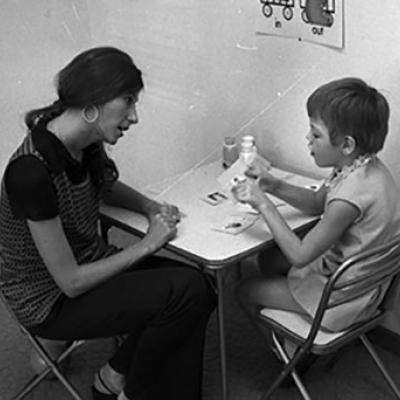teacher works with a special needs child, at a small table with teaching aids