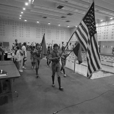 group of 5 young men in Boy Scout uniforms, 3 of which are holding flags