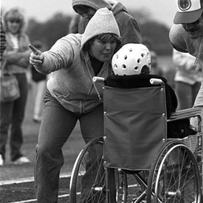  a Special Olympics wheelchair participant gets direction from a volunteer along the track