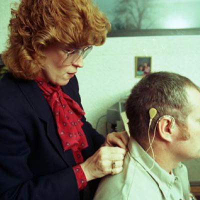 woman hooks up a new hearing device, a cochlear implant
