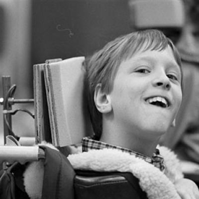 Sean Pevsner, a child with cerebral palsy, uses a special headrest to work with a computer