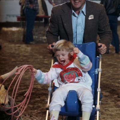 Rodeo for disabled children; cowboy Brad Barnes gives Chanin Aiken a push