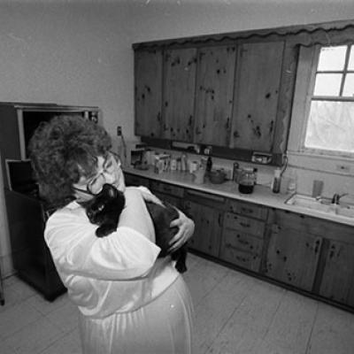 Cathy  snuggles the house cat, Mama Kitty, in kitchen