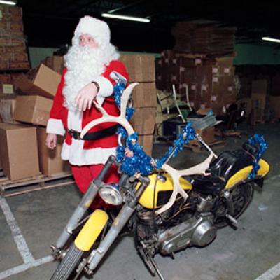 Santa Claus rides a vintage 1940s yellow Harley-Davidson with antlers