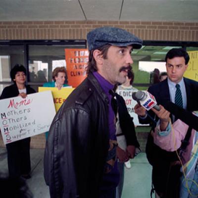 Brad Eddins talks to the media during a rally for better AIDS services