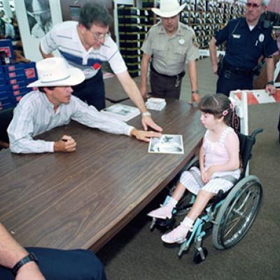 Young fan in a wheelchair receives an autographed photo from country singer George Strait