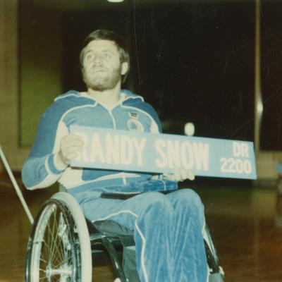 Randy Snow holding street sign during Handicap Awareness Week